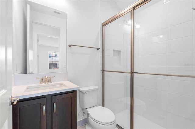 bathroom featuring vanity, a shower with door, and toilet