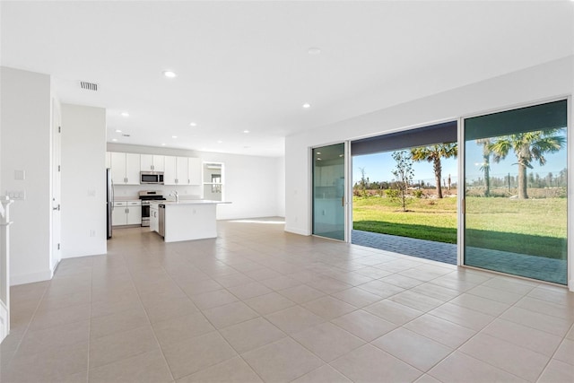 unfurnished living room featuring light tile patterned floors and sink