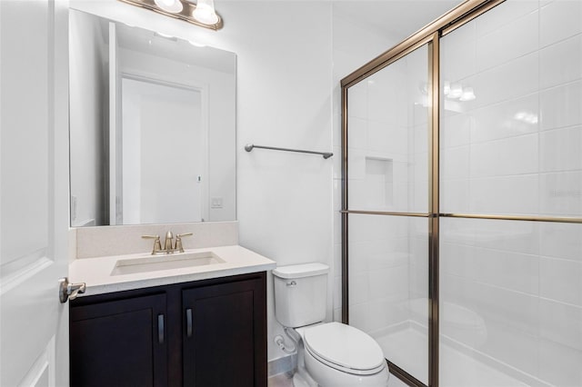 bathroom with toilet, vanity, and a shower with shower door