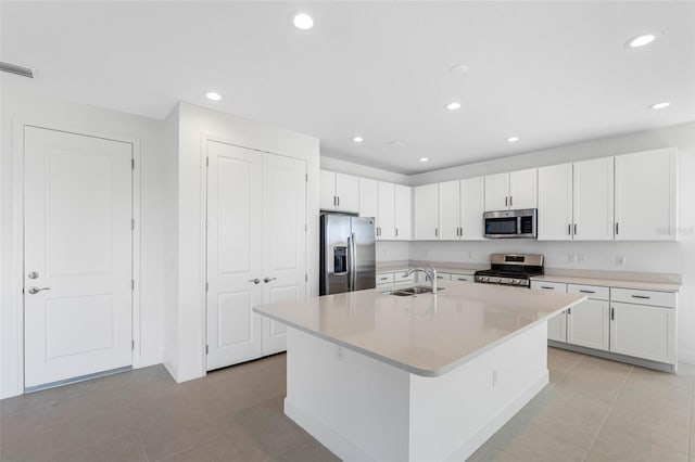 kitchen with a center island with sink, sink, light tile patterned floors, appliances with stainless steel finishes, and white cabinets