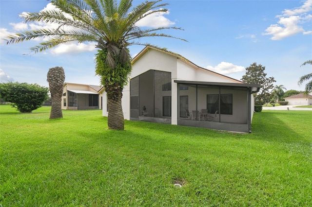 rear view of house with a yard and a sunroom