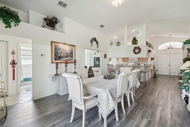 dining room featuring high vaulted ceiling and dark hardwood / wood-style flooring