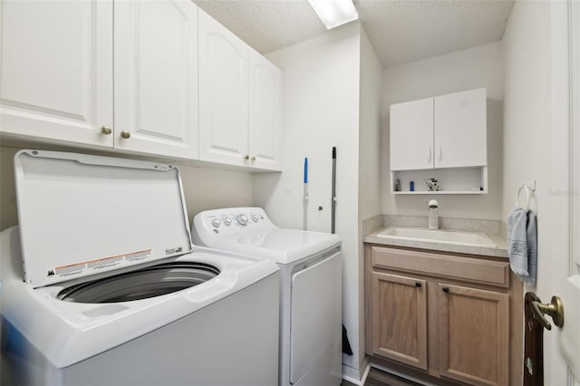 clothes washing area featuring sink, independent washer and dryer, a textured ceiling, and cabinets