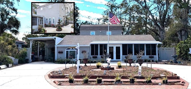 view of front of home featuring driveway, a sunroom, fence, and a carport