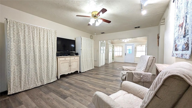 living room with a ceiling fan, visible vents, a textured ceiling, and wood finished floors