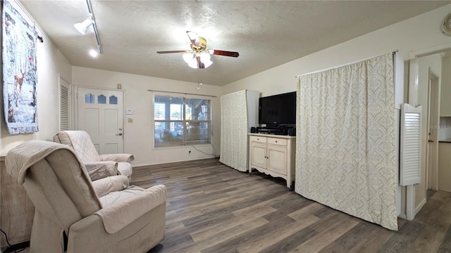 living room with a textured ceiling, dark wood-type flooring, and a ceiling fan