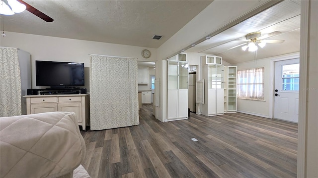 interior space with visible vents, dark wood-type flooring, freestanding refrigerator, a ceiling fan, and a textured ceiling