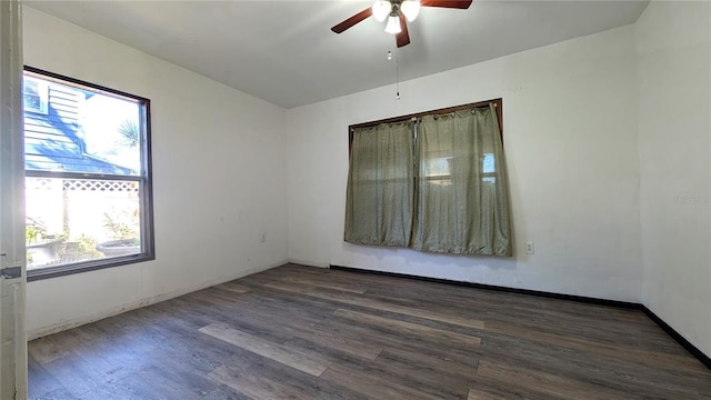 spare room featuring dark wood-style floors, ceiling fan, and baseboards