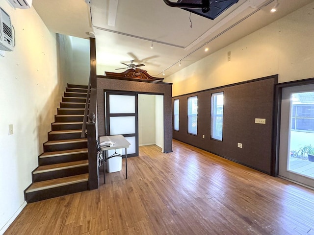 unfurnished room with a ceiling fan, a healthy amount of sunlight, stairway, and wood finished floors