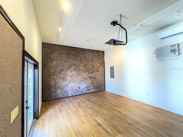 spare room with rail lighting, an AC wall unit, a wall unit AC, and wood finished floors