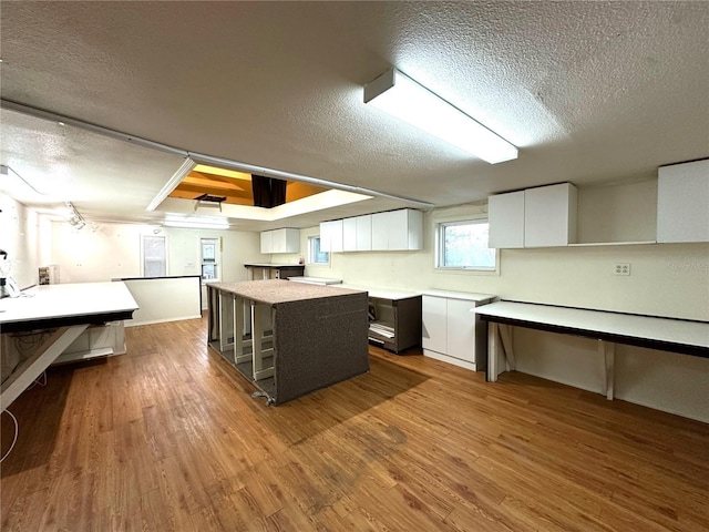 kitchen featuring modern cabinets, a center island, light countertops, light wood-style floors, and white cabinetry