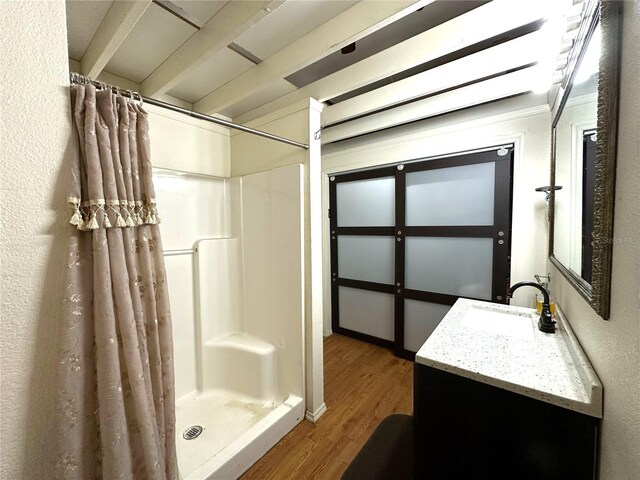 full bath with a stall shower, a textured wall, vanity, and wood finished floors