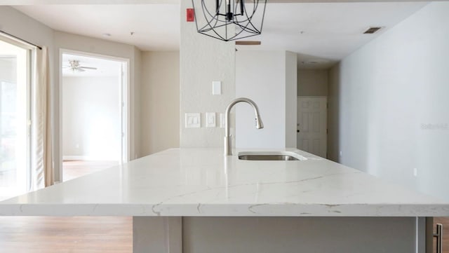 kitchen featuring plenty of natural light, ceiling fan with notable chandelier, sink, and hanging light fixtures