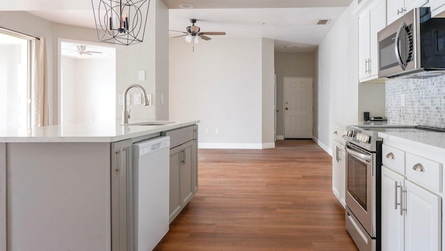 kitchen with light hardwood / wood-style floors, a chandelier, tasteful backsplash, stainless steel appliances, and white cabinetry