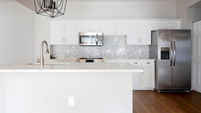 kitchen with white cabinets, decorative light fixtures, a kitchen island with sink, stainless steel appliances, and dark hardwood / wood-style flooring