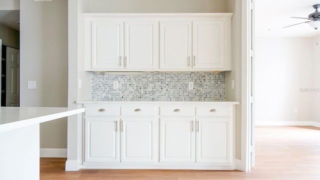 kitchen featuring tasteful backsplash, light wood-type flooring, and white cabinets