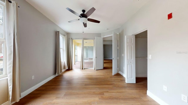 unfurnished bedroom featuring ceiling fan, light wood-type flooring, and multiple windows