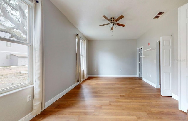 empty room with ceiling fan, a wealth of natural light, and light hardwood / wood-style floors