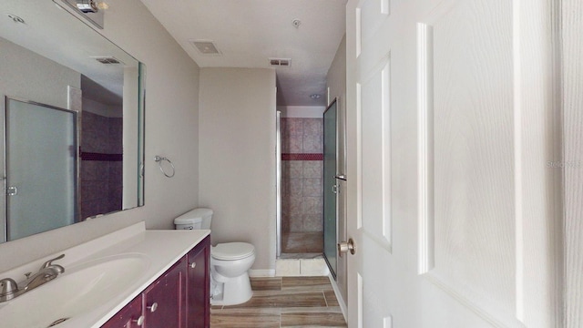 bathroom featuring vanity, a shower with door, toilet, and wood-type flooring