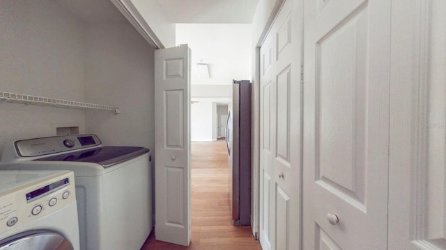 laundry room with washer and clothes dryer and light wood-type flooring