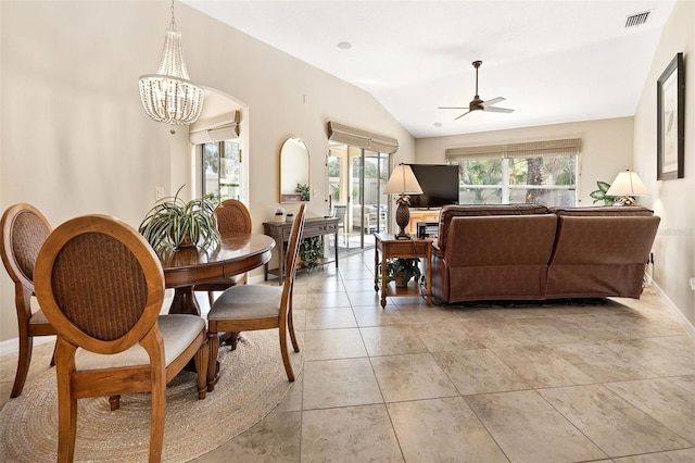 tiled dining space featuring ceiling fan with notable chandelier and vaulted ceiling