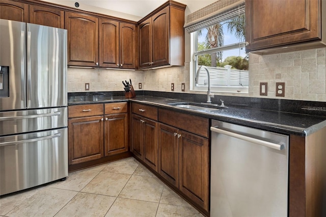 kitchen featuring light tile patterned flooring, dark stone counters, sink, stainless steel appliances, and backsplash