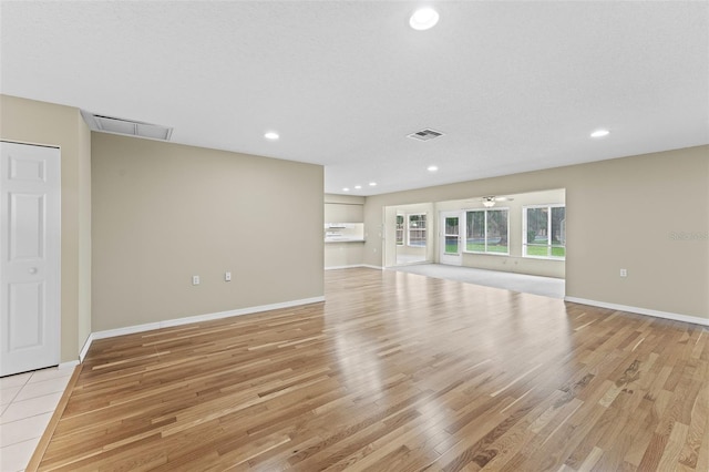 unfurnished living room featuring a textured ceiling, light wood-type flooring, and ceiling fan