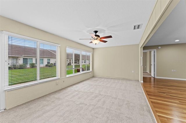 unfurnished room with a wealth of natural light, light hardwood / wood-style flooring, a textured ceiling, and ceiling fan