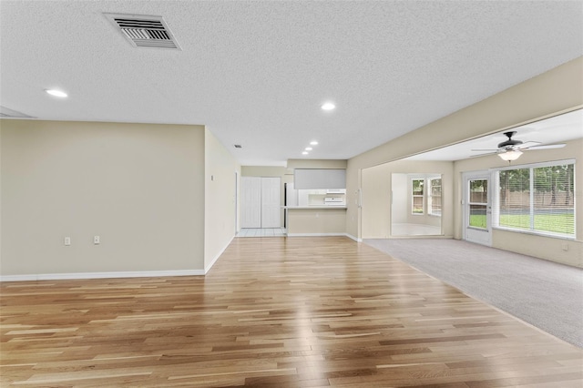 unfurnished living room featuring a textured ceiling, light colored carpet, and ceiling fan