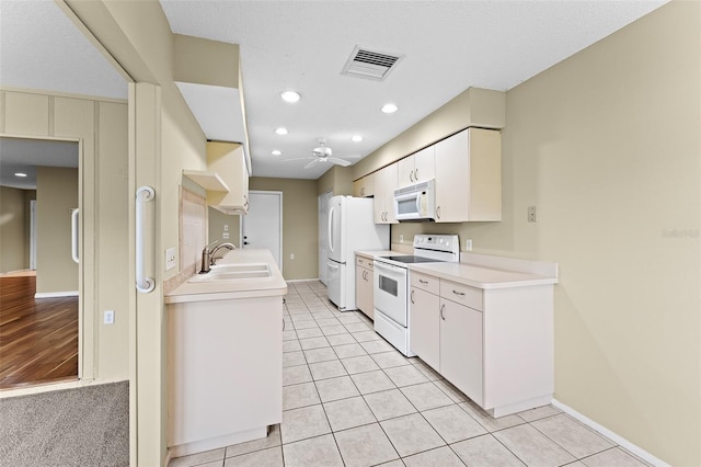 kitchen featuring sink, white cabinetry, white appliances, and light tile patterned floors