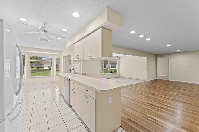 kitchen with sink, light wood-type flooring, dishwasher, kitchen peninsula, and white fridge