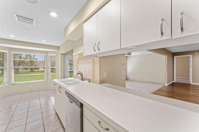 kitchen featuring white cabinets, stainless steel dishwasher, sink, and a textured ceiling