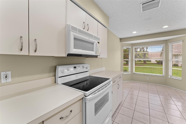 kitchen featuring white cabinets, a textured ceiling, white appliances, and light tile patterned floors