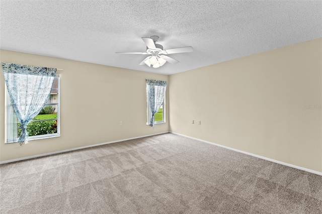 carpeted empty room featuring ceiling fan, a textured ceiling, and a wealth of natural light