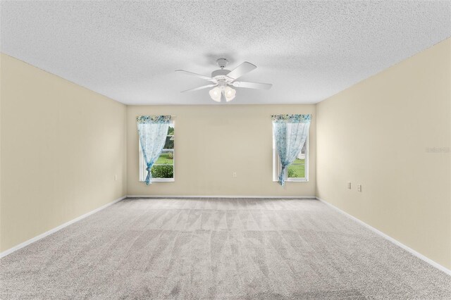 carpeted empty room featuring a textured ceiling, a healthy amount of sunlight, and ceiling fan