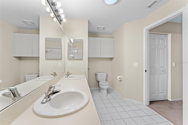 bathroom featuring toilet, a textured ceiling, vanity, and tile patterned floors