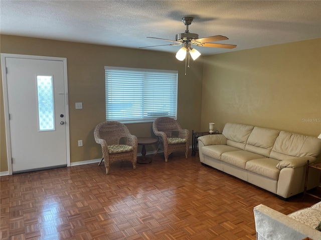 living room with ceiling fan, a textured ceiling, and parquet floors