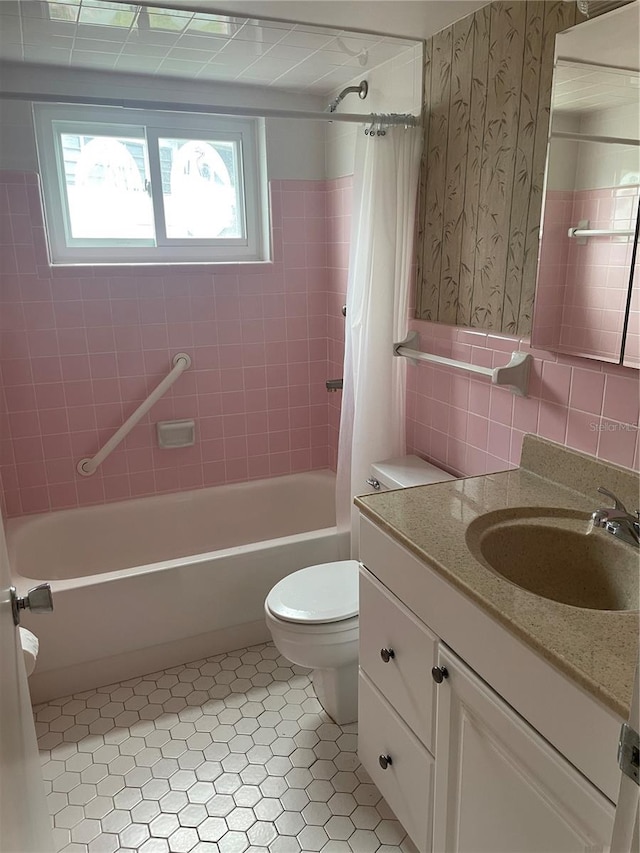 full bathroom with shower / bathtub combination with curtain, tile walls, toilet, vanity, and tile patterned flooring