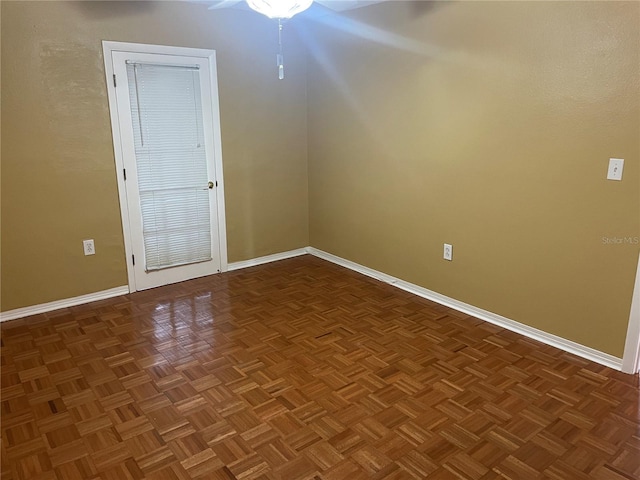 spare room featuring ceiling fan and dark parquet floors