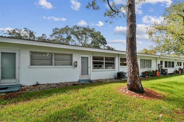 ranch-style house with central air condition unit and a front yard