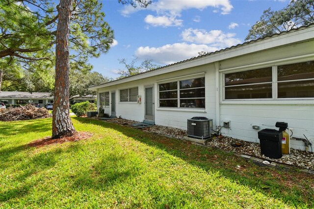 view of home's exterior with a lawn and central AC