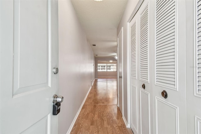 hall featuring a textured ceiling and light wood-type flooring