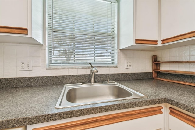 kitchen with decorative backsplash, white cabinetry, and sink