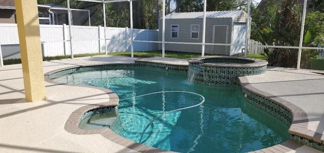 view of swimming pool featuring a lanai, a patio, a storage shed, and an in ground hot tub