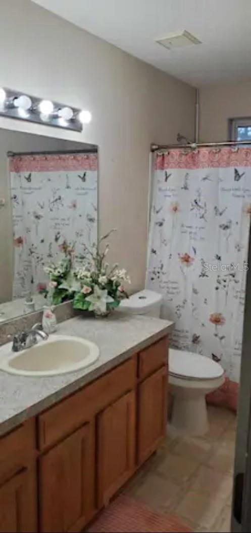 bathroom with walk in shower, vanity, and toilet