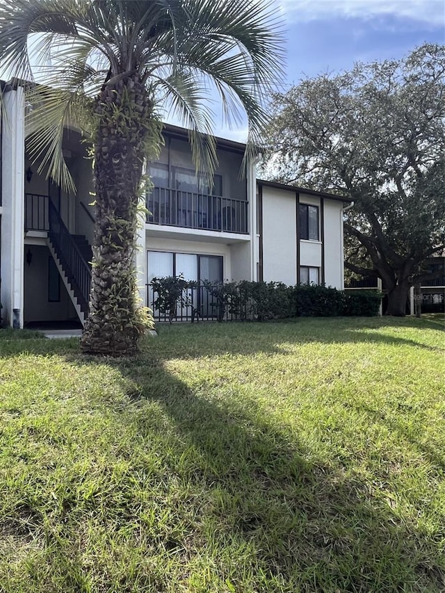 2688 Pine Ridge Way N Unit D1, Palm Harbor, FL 34684 - back of house with stucco siding, a yard, and stairs