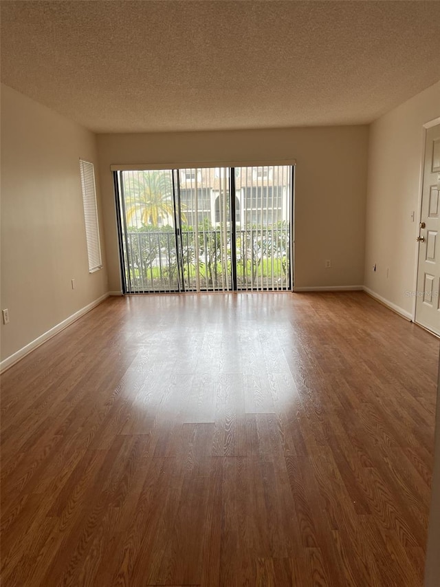 spare room featuring wood-type flooring and a textured ceiling