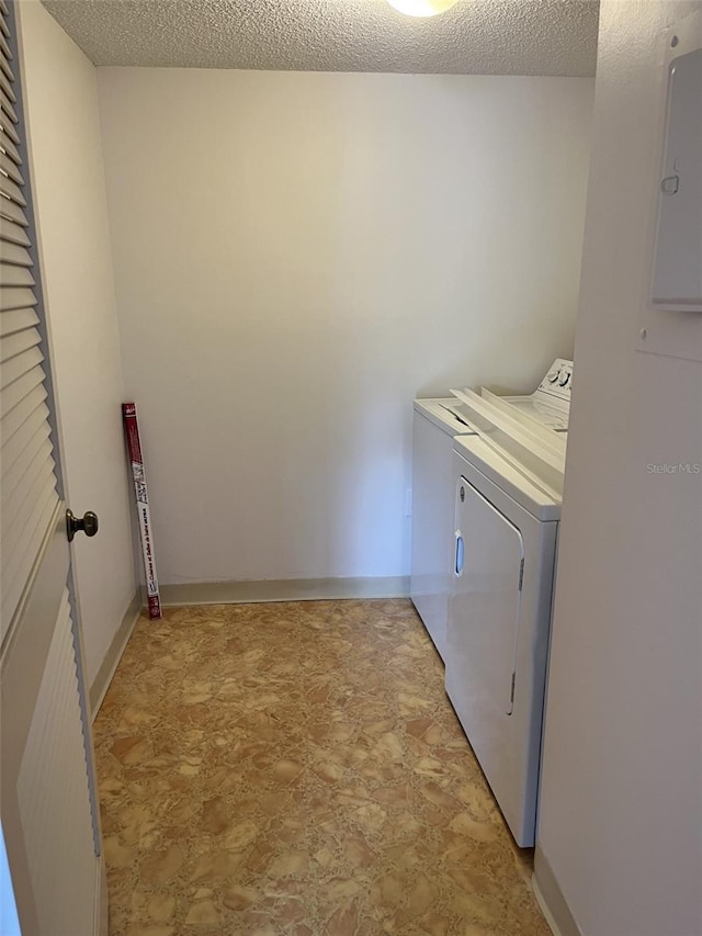 laundry room with electric panel, washing machine and dryer, and a textured ceiling