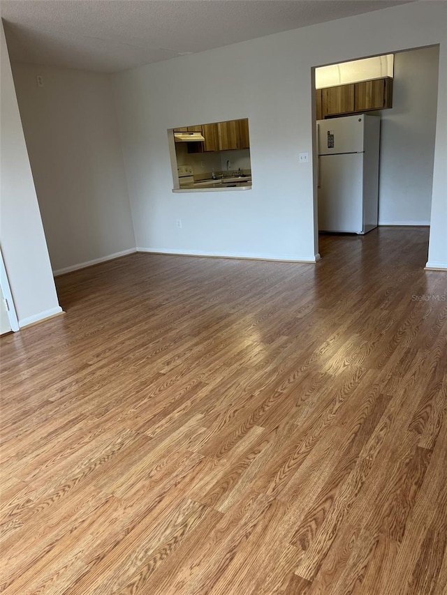 2688 Pine Ridge Way N Unit D1, Palm Harbor, FL 34684 - unfurnished living room featuring dark wood-type flooring, baseboards, and a sink