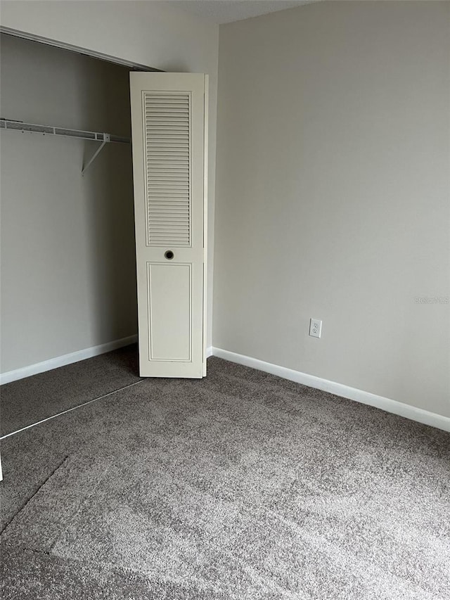 unfurnished bedroom featuring a closet and dark carpet